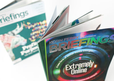 A photo of Korn Ferry Briefings printed catalogs with holographic text and embossed accents