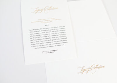 A photo of printed wine cards for Quintessa's Legacy Collection, produced by Qualprint with gold foil embossing and custom envelope