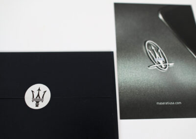 A photo of a printed direct mail piece for Maserati with Silver foil accents and soft touch laminate