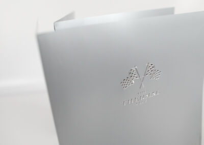 A photo of a custom folder for The Thermal Club with embossed silver foil accents produced by Qualprint