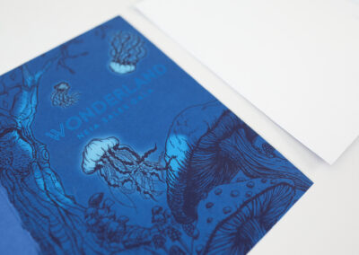 A photo of a printed invitation to the NEIA Sales Gala produced by Qualprint with blue foil embossing and white ink