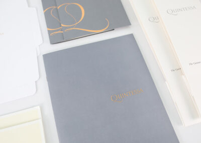 A photo of retail marketing collateral for Quintessa, produced by Qualprint with gold foil accents, embossed text and custom packaging